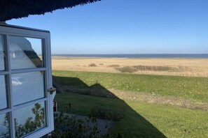 A room with a large window overlooking a grassy field and a clear sky. - "Dream view" in the Sölring-Hüs (Sylt\/OT Rantum)