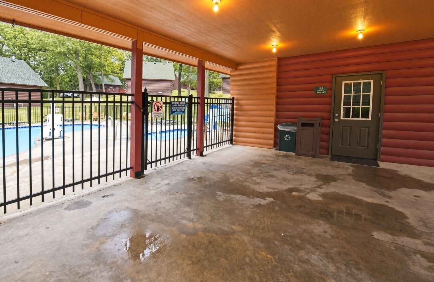 Un espacio al aire libre cubierto con una piscina, una zona cercada y una puerta que dice 'Loo Cabin Laundry'.