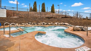 A hot tub area with a stone wall and a fence in the background.
