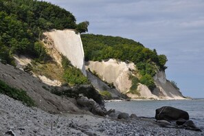 A coastal landscape with a prominent cliff, a pebble beach, and a body of water. - Holiday home in Glowe with swimming pool (Glowe)