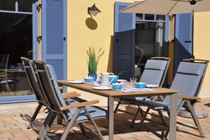 An outdoor dining area with a table, chairs, and a potted plant. - Holiday home in Glowe with swimming pool (Glowe)