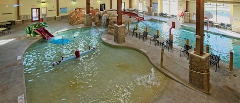 An indoor swimming pool with multiple lanes, a slide, and a waterfall feature.