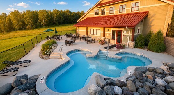 A swimming pool with a hot tub, surrounded by lounge chairs and a patio area.