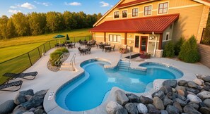 Une piscine avec un jacuzzi, entourée de chaises longues et d’un espace patio.