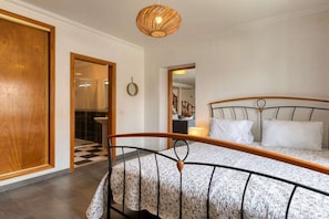 Ein Schlafzimmer mit einem Bett, einer Holztür, einem Schachbrettfußboden und einer Pendelleuchte.