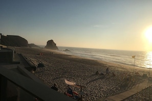 A beach with a rocky outcrop, a wooden boardwalk, and a flag.