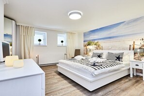 Quarto com cama, mesas de cabeceira, cômoda e vista para a praia.