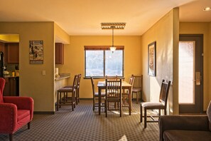 Un coin repas avec une table et des chaises, une fenêtre donnant sur un beau paysage et un fauteuil rouge.