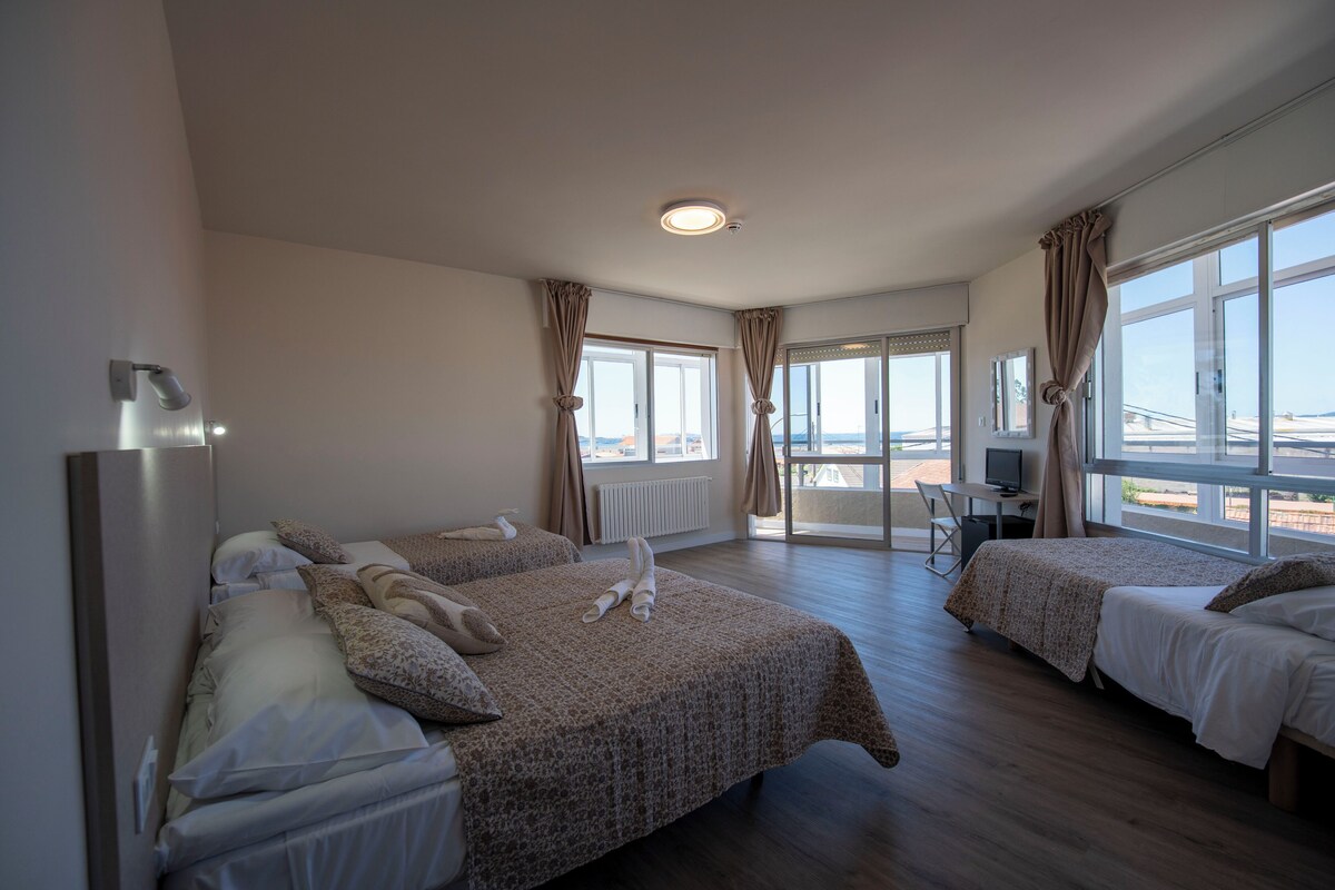 A hotel room with two beds, a desk with a computer, and large windows offering a view of a bridge.
