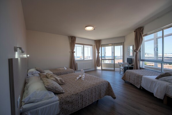 A hotel room with two beds, a desk with a computer, and large windows offering a view of a bridge.