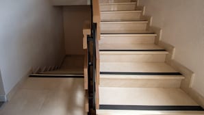 Una escalera con peldaños color beige y laterales negros que lleva a un piso superior.