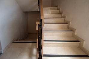 A staircase with beige steps and black risers, leading to an upper floor.