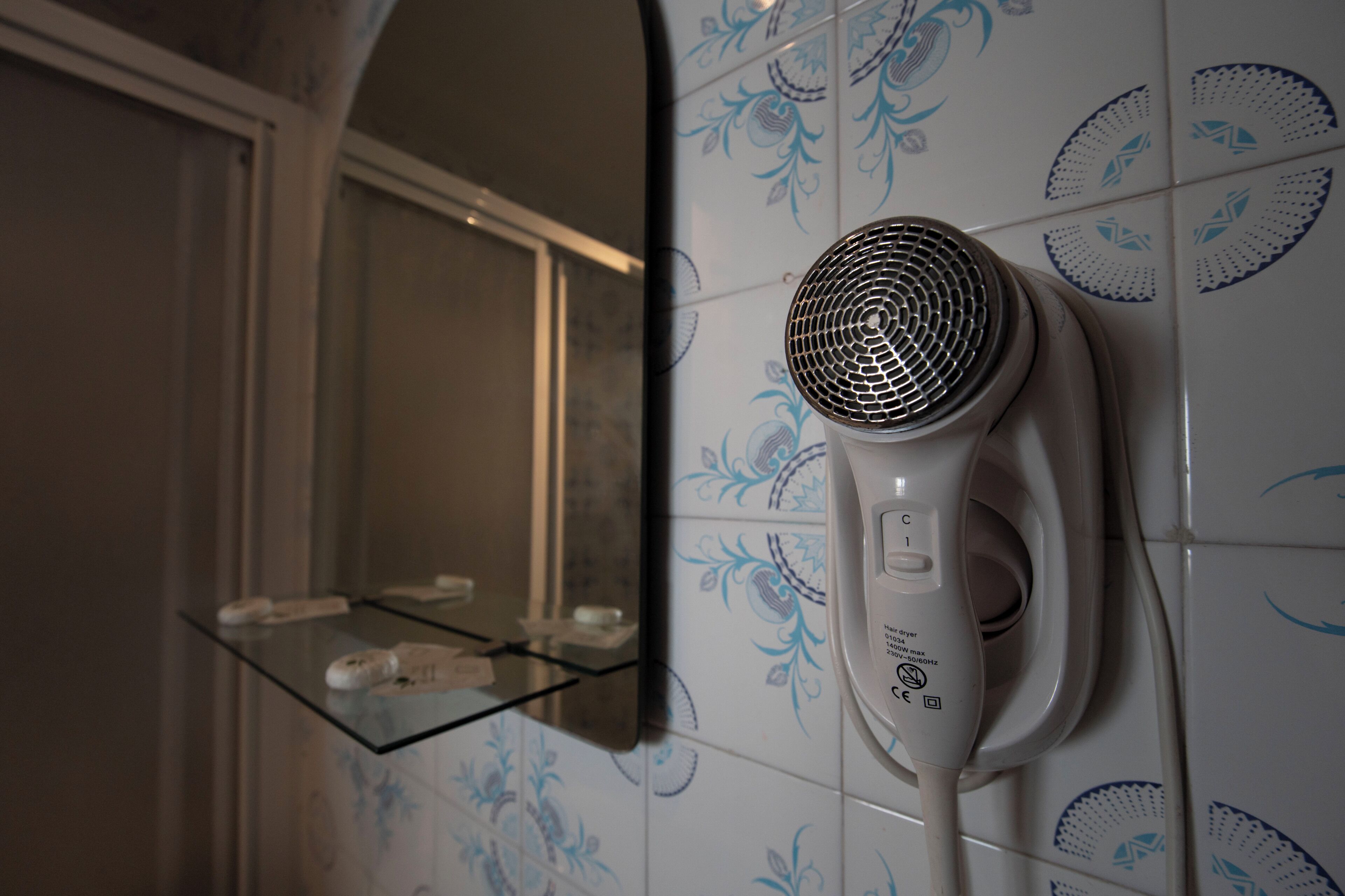 Een haardroger bevestigd aan een wand met getegelde patronen.