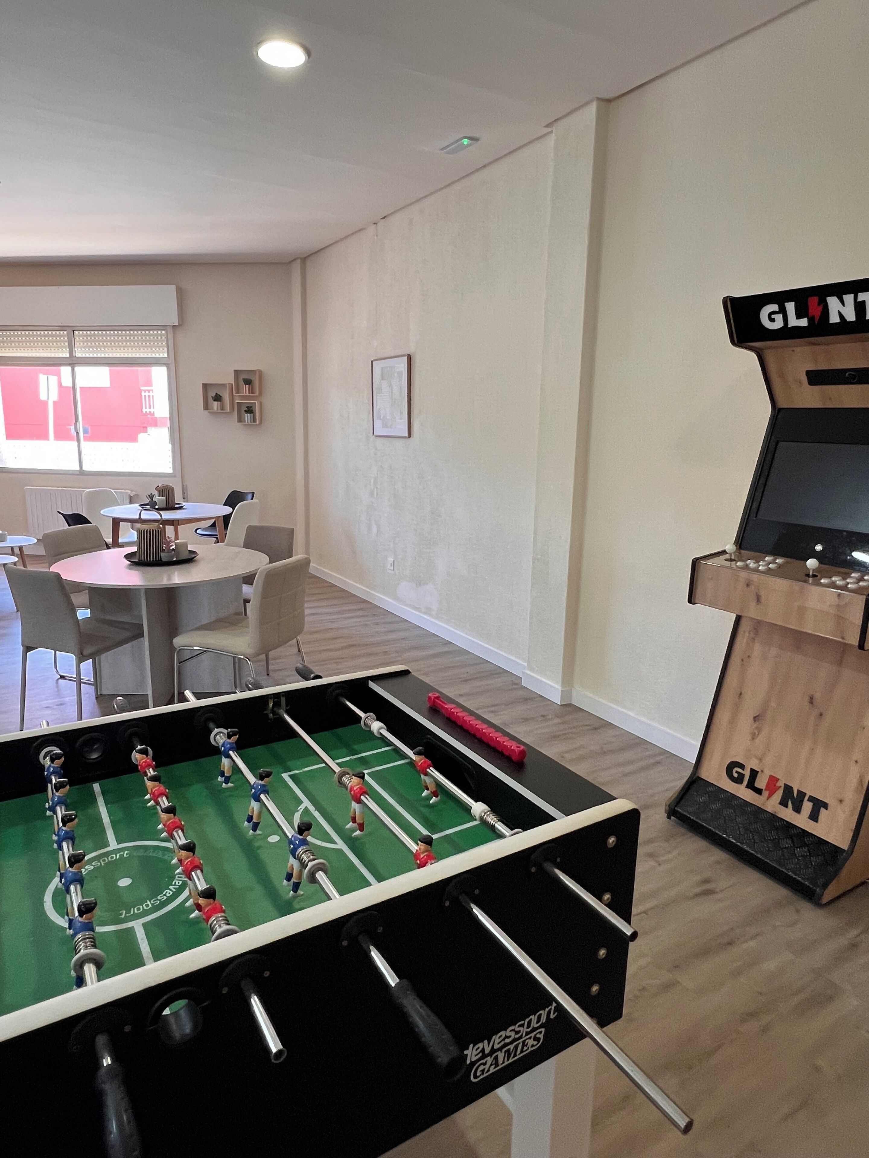 Een kamer met een tafelvoetbaltafel, een kleine televisie en een tafel met stoelen.