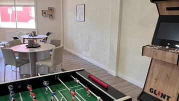 Een kamer met een tafelvoetbaltafel, een kleine televisie en een tafel met stoelen.