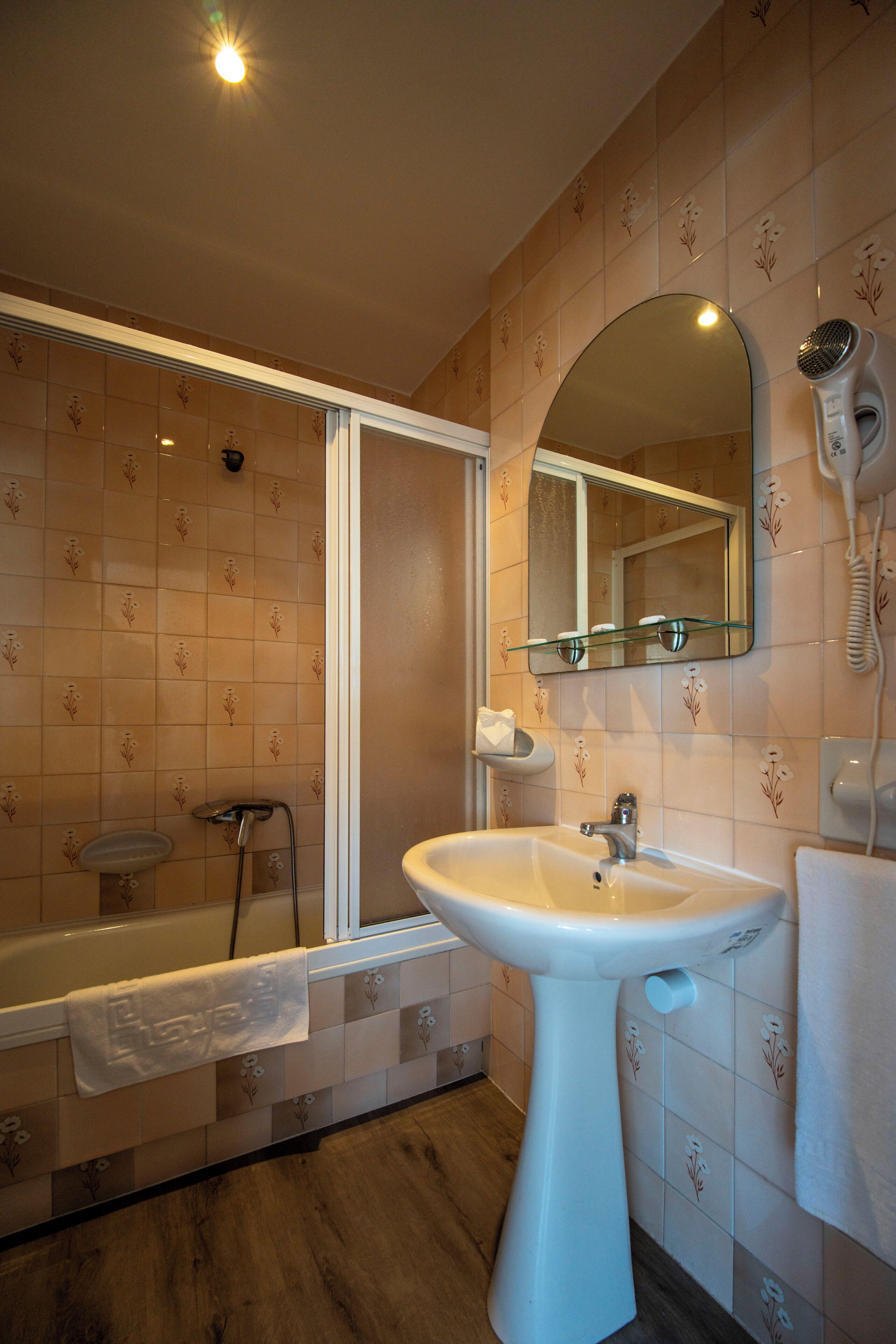 Ein Badezimmer mit Badewanne, Waschbecken, Spiegel und Fön.
