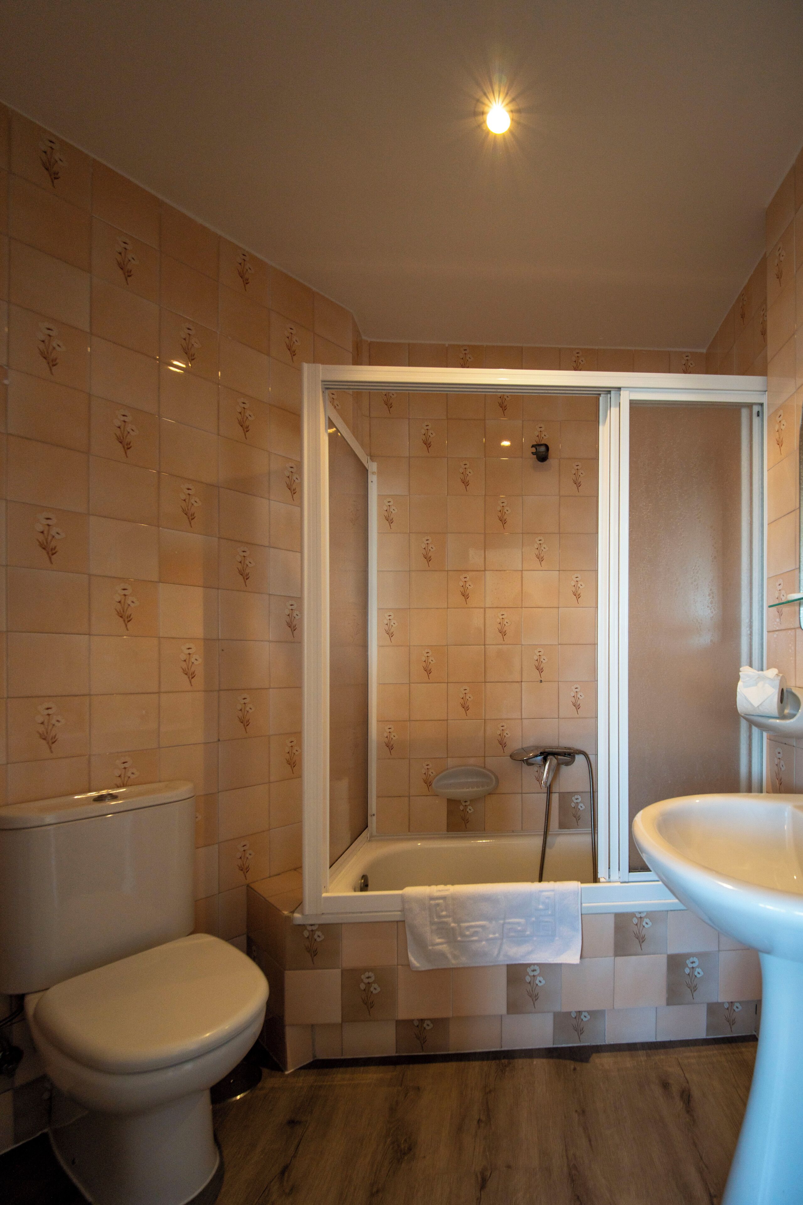 A bathroom with a toilet, a sink, and a bathtub with a shower head.