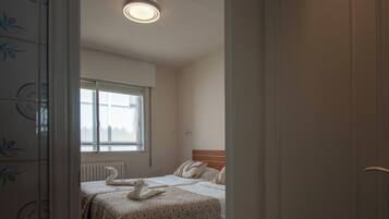 Una habitación de hotel con una cama, ventana, radiador y puerta.