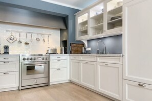 A kitchen with white cabinets, stainless steel appliances, and a blue accent wall. - Penthouse Maison Plage (Scharbeutz)