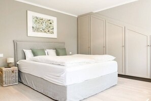 A bedroom with a bed, a bedside table with a lamp, a framed picture on the wall, and a wardrobe. - Penthouse Maison Plage (Scharbeutz)