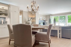 A modern kitchen with a dining area, a chandelier, and a view of the outdoors. - Penthouse Maison Plage (Scharbeutz)