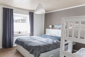 Una camera da letto con un letto, una culla, una finestra con tende e una lampada a sospensione.
