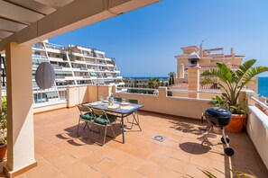 A terrace with a table set for dining, a grill, and potted plants. - Cubo's Benalmadena Apartment Pool & Parking / communal pool / air conditioning / terrace / BBQ (Benalmádena)
