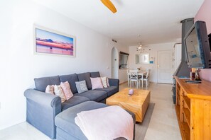 A living room with a grey sofa, a coffee table, and a painting of a sunset. - Cubo's Benalmadena Apartment Pool & Parking / communal pool / air conditioning / terrace / BBQ (Benalmádena)