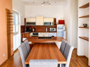 A modern kitchen with wooden cabinetry, a central island, and a dining area with grey upholstered chairs. - Vacation Rental with Ocean View (Sassnitz)