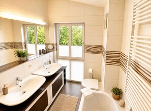 A modern bathroom with two sinks, a bathtub, and a toilet. - Vacation Rental with Ocean View (Sassnitz)