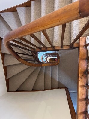 A spiral staircase with a wooden handrail and beige carpeted steps. - Cairnhill | Characterful Highland Home near Royal Dornoch (Dornoch)