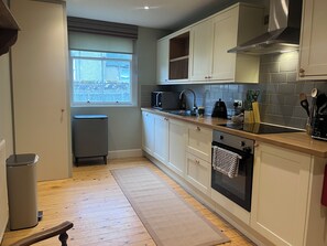 A kitchen with white cabinets, a stainless steel range hood, a microwave, and a dishwasher. - Cairnhill | Characterful Highland Home near Royal Dornoch (Dornoch)