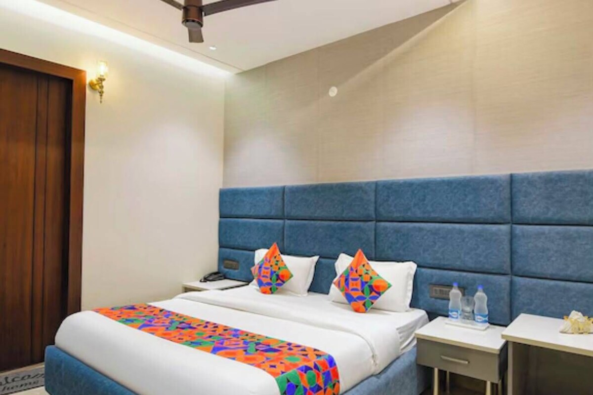 Een hotelkamer met een bed, nachtkastje, plafondventilator en een deur.