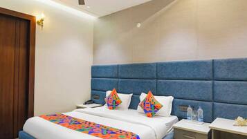 A hotel room with a bed, a nightstand, a bedside table, a ceiling fan, and a door.