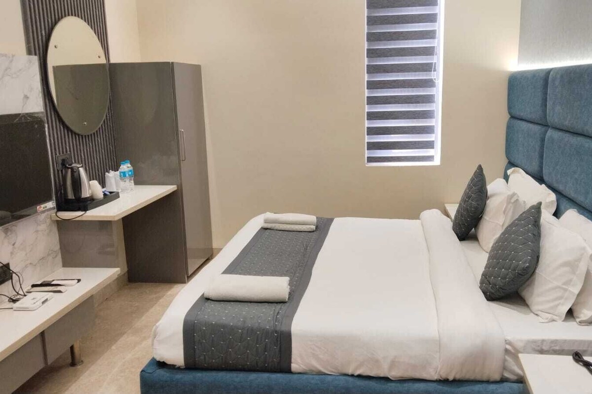 Een hotelkamer met een bed, nachtkastje en een bureau met stoel.