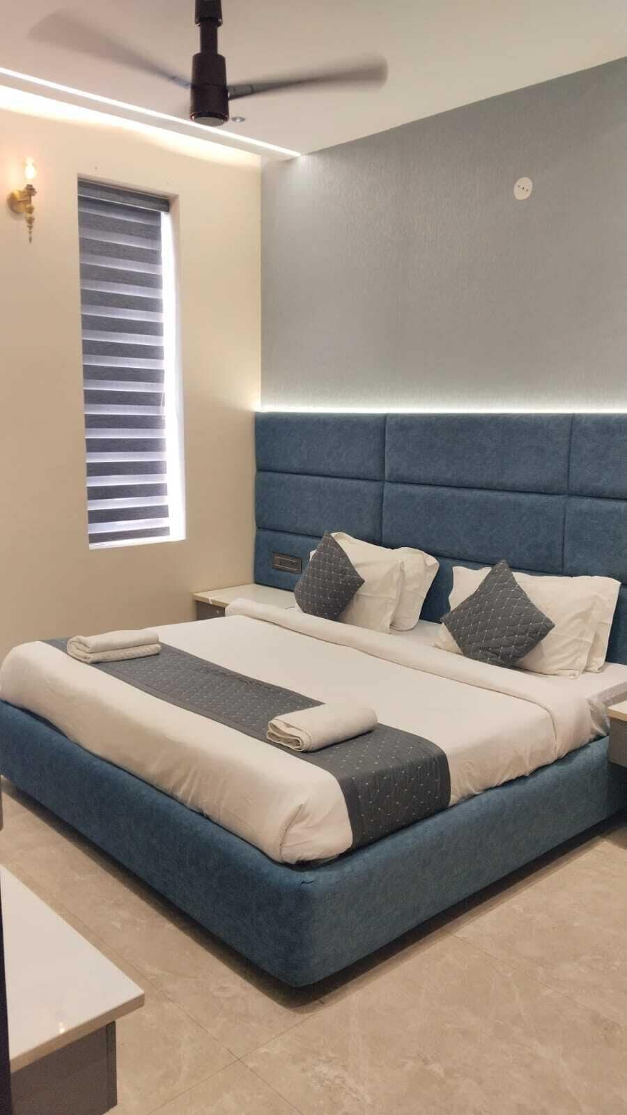 A modern bedroom with a large bed, a ceiling fan, and a window with blinds.