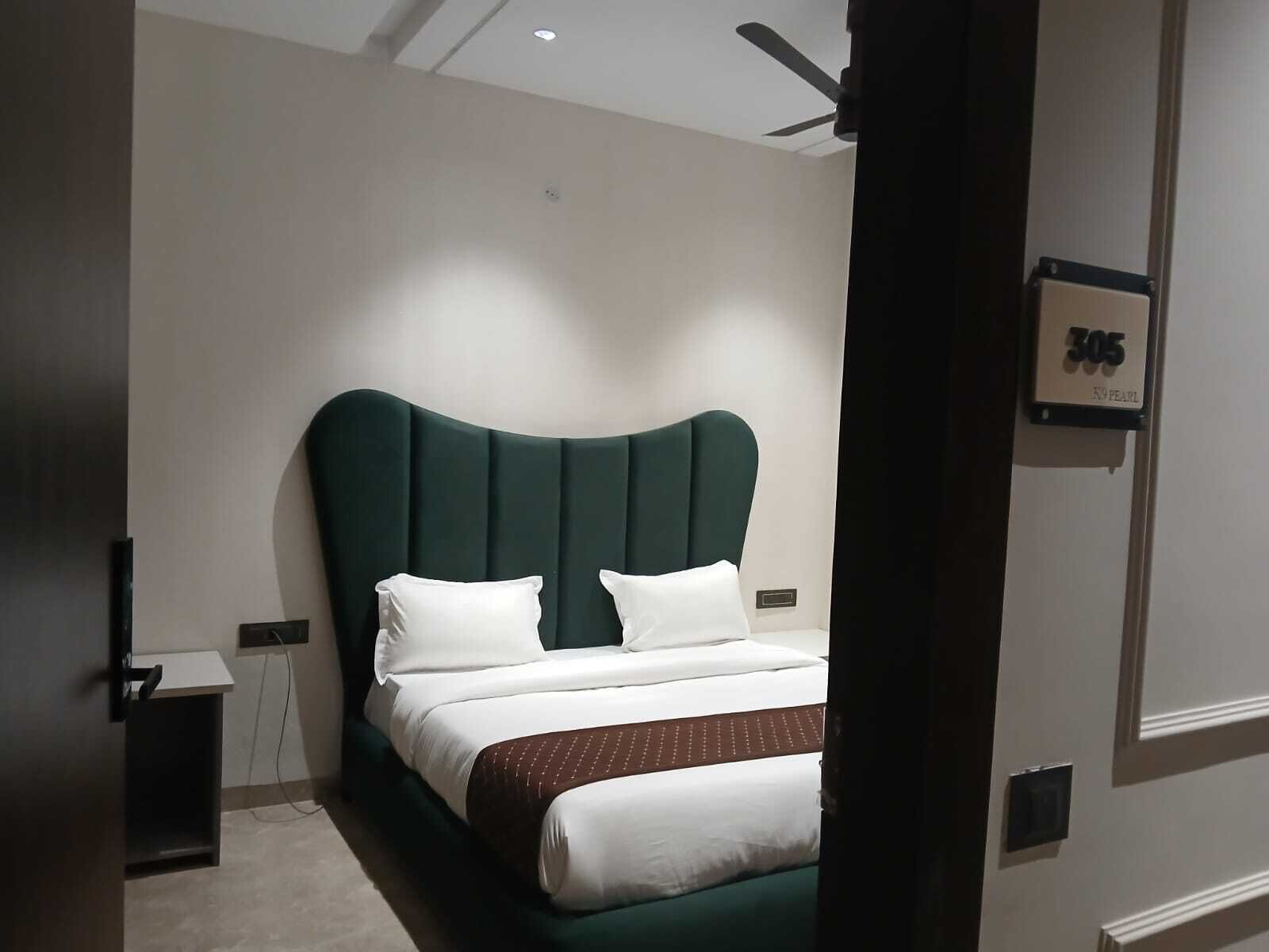 Una habitación de hotel moderna con una cama grande, un ventilador de techo y una puerta con un letrero de número.