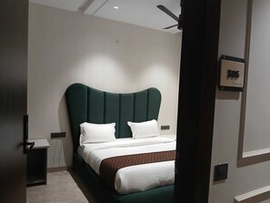 Een moderne hotelkamer met een groot bed, een plafondventilator en een deur met nummerbord.