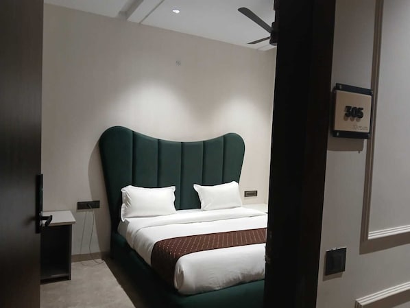Une chambre d’hôtel moderne avec un grand lit, un ventilateur de plafond et une porte portant un numéro.
