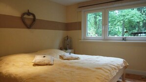 Une chambre à coucher avec un lit, une fenêtre donnant sur des arbres et un décor en forme de cœur sur le mur.