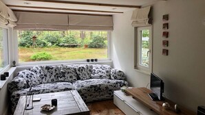 Une pièce chaleureuse avec un canapé à motifs, une table en bois et un ordinateur posé sur un bureau.