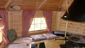 Interior acogedor de una cabaña con detalles de madera, una chimenea y cortinas de cuadros.