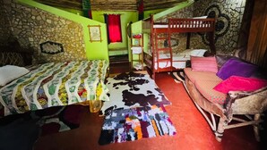 Una habitación con dos literas, una pared de piedra, una alfombra colorida y un techo de madera.