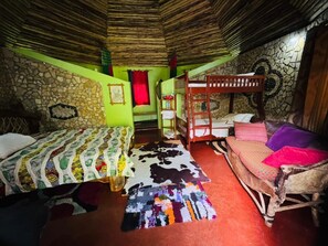 A room with two bunk beds, a stone wall, a colorful rug, and a wooden ceiling. - Songota Falls Retreat (Arusha)