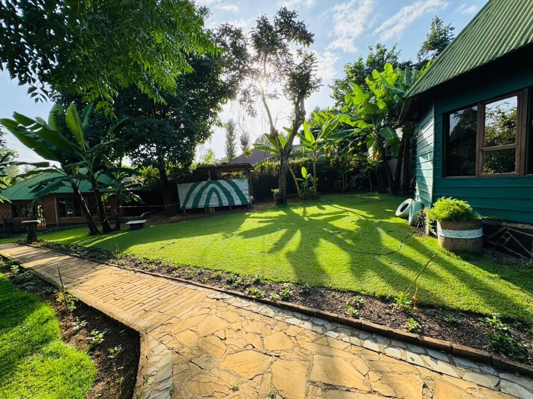 Un jardín cuidado con un sendero de piedra que lleva a una casa con techo verde.