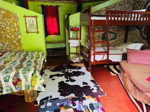 Habitación con literas, pared de piedra, colcha acolchada y alfombra de cuero.