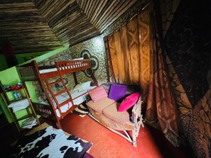A room with a bunk bed, a sofa with cushions, a patterned curtain, and a stone wall. - Songota Falls Retreat (Arusha)