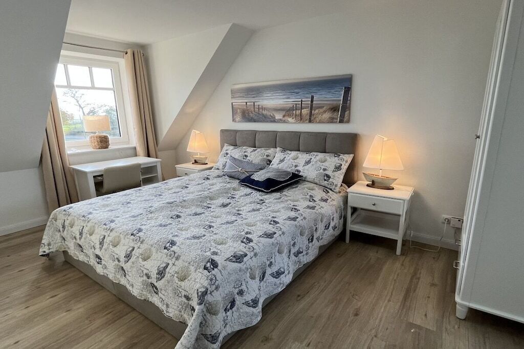 Une chambre à coucher avec un lit, des tables de chevet, une fenêtre et un tableau accroché au mur.
