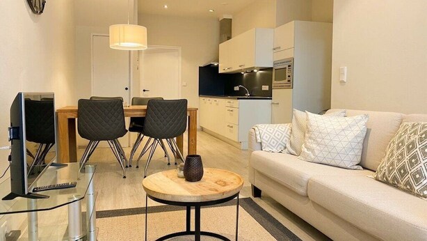 A compact living space with a dining area, kitchenette, and a sofa with patterned cushions. - DO19 Holiday home Domburg (Domburg)