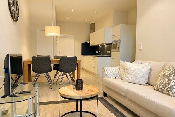 A compact living space with a dining area, kitchenette, and a sofa with patterned cushions. - DO19 Holiday home Domburg (Domburg)